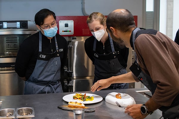 Dos alumnos y un profesor dando feedback de la evaluación de aprendizajes del Culinary Institute of Barcelona